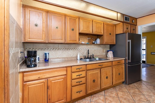 kitchen featuring a sink, light countertops, freestanding refrigerator, brown cabinets, and open shelves