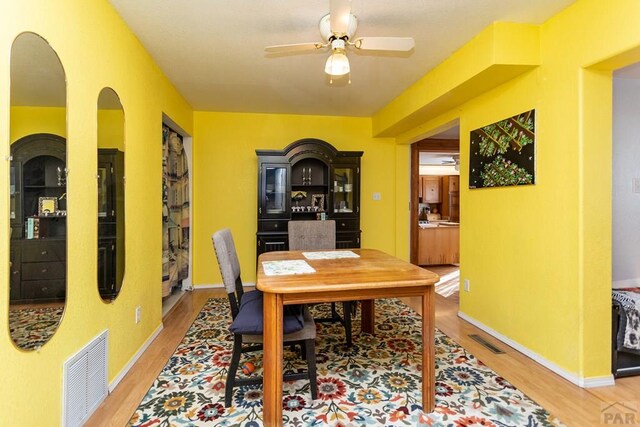 dining area featuring baseboards, wood finished floors, visible vents, and a ceiling fan