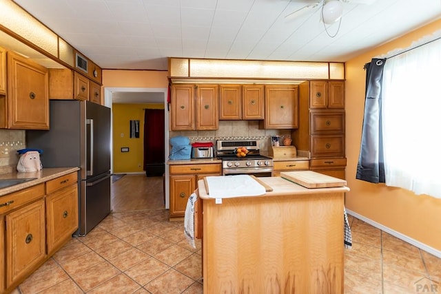 kitchen with brown cabinetry, stainless steel appliances, decorative backsplash, and a center island