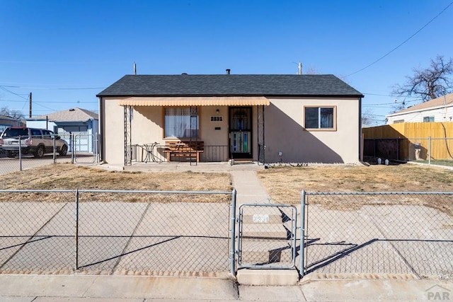 bungalow-style house featuring a fenced front yard, a gate, a shingled roof, and stucco siding