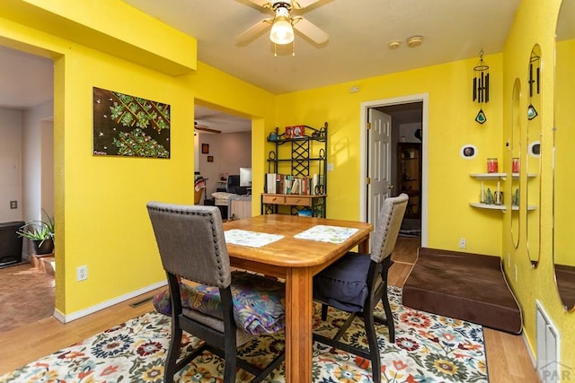 dining room featuring light wood-style floors, visible vents, ceiling fan, and baseboards