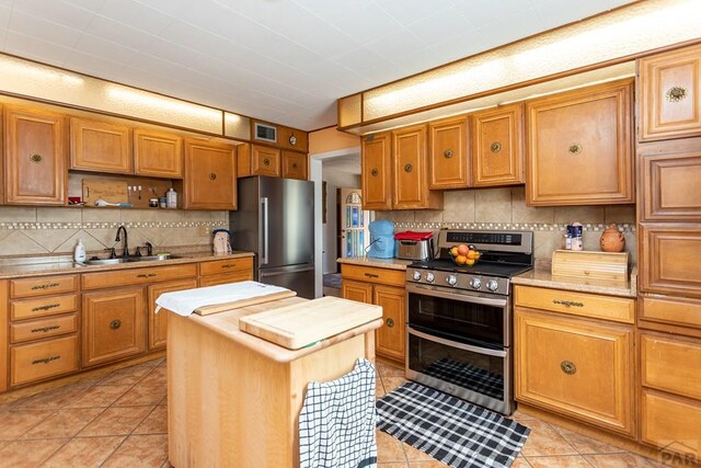 kitchen featuring appliances with stainless steel finishes, visible vents, a sink, and backsplash