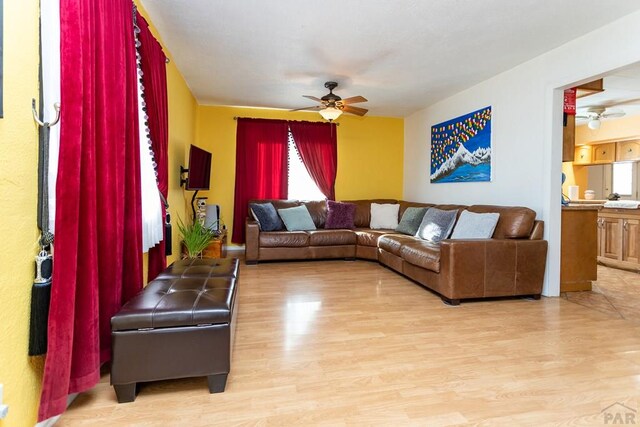 living area with light wood-type flooring and a ceiling fan