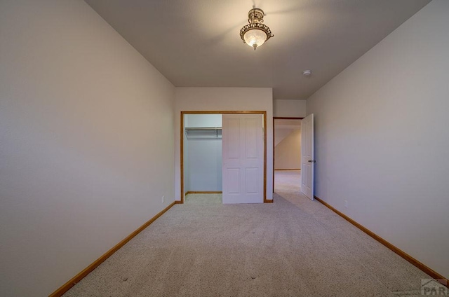 unfurnished bedroom with baseboards, light colored carpet, and a closet