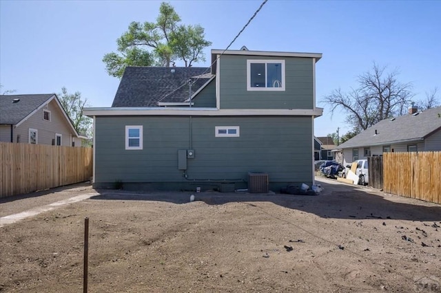 rear view of property featuring a fenced backyard and central AC