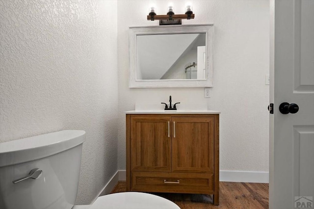 bathroom with baseboards, wood finished floors, vanity, and toilet