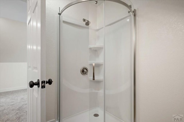 full bathroom with a shower stall and baseboards