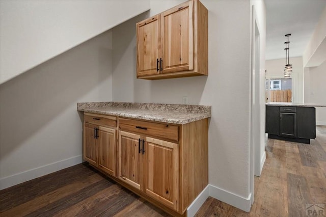 bar featuring baseboards, hanging light fixtures, and dark wood-style flooring