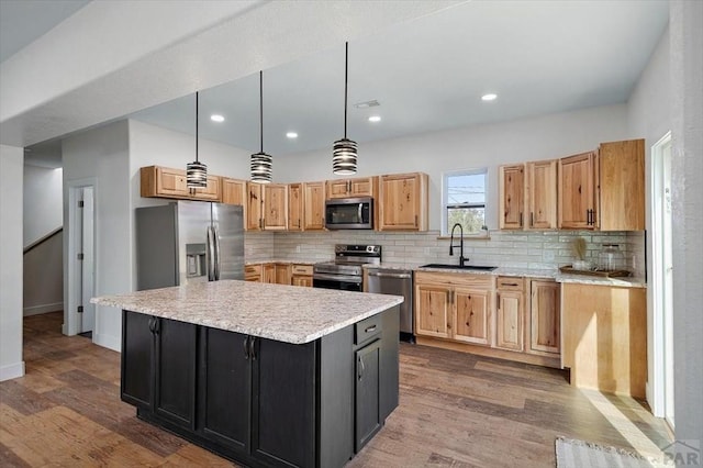 kitchen with a center island, tasteful backsplash, a sink, appliances with stainless steel finishes, and dark wood-type flooring