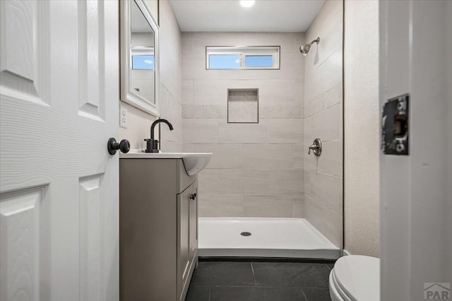 bathroom featuring tile patterned floors, vanity, tiled shower, and toilet