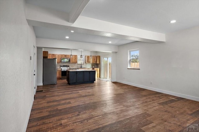 kitchen featuring brown cabinetry, open floor plan, light countertops, baseboards, and appliances with stainless steel finishes