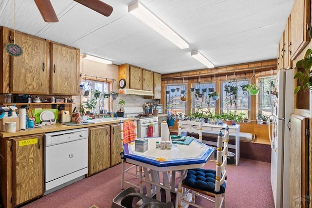 kitchen with a sink, white appliances, brown cabinets, and light countertops