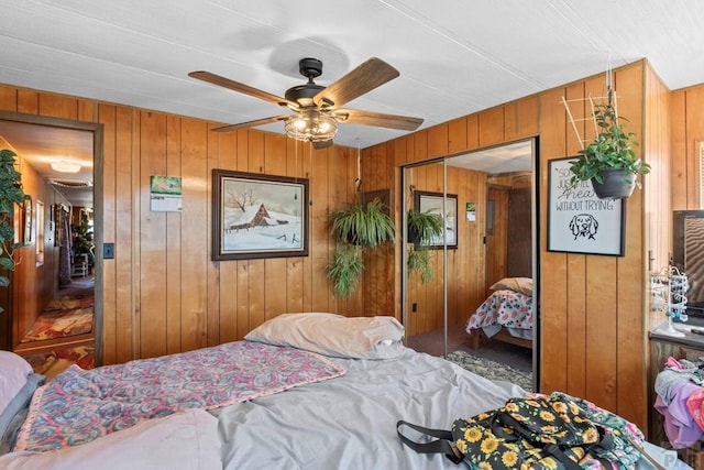 bedroom with a ceiling fan, a closet, and wooden walls