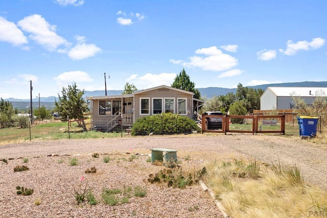 view of front of house with a gate, a mountain view, and fence