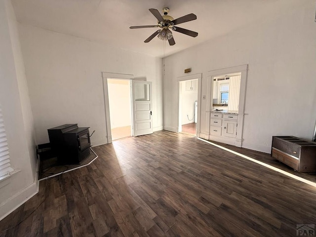 504 Sherman Ave, Ordway, CO 81063 - unfurnished living room featuring a wood stove, a ceiling fan, and dark wood-type flooring