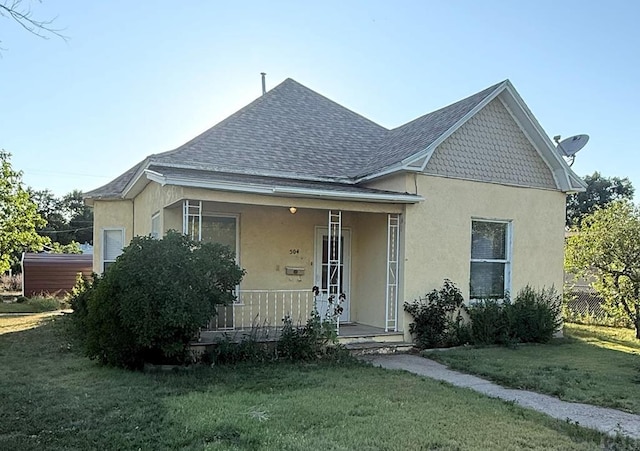 504 Sherman Ave, Ordway, CO 81063 - view of front of home with covered porch, stucco siding, a front lawn, and roof with shingles