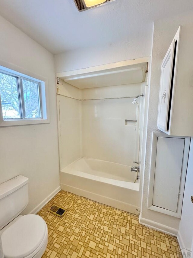 bathroom with toilet, washtub / shower combination, visible vents, and baseboards