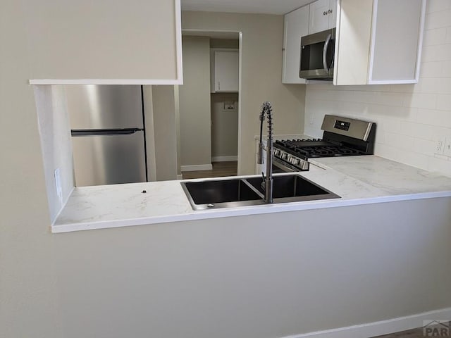 kitchen with decorative backsplash, white cabinetry, appliances with stainless steel finishes, and a sink