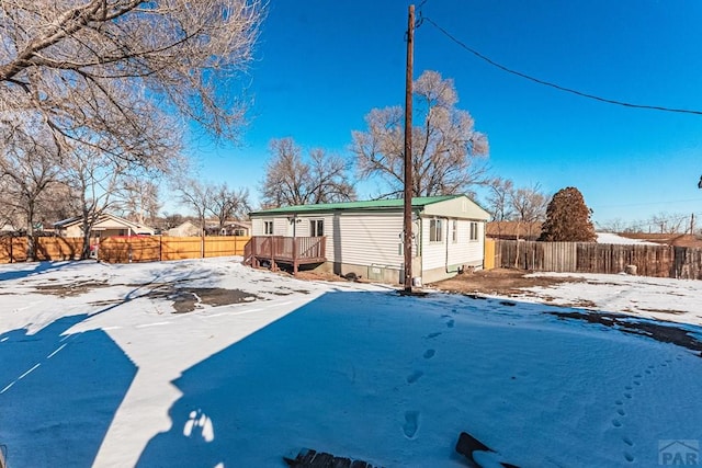 yard covered in snow featuring a fenced backyard and a wooden deck