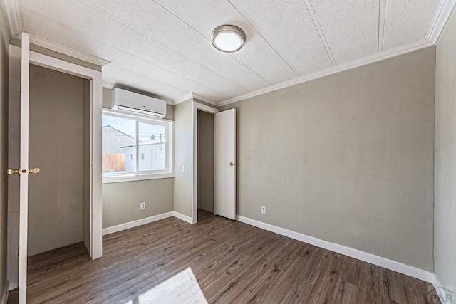 unfurnished bedroom featuring baseboards, wood finished floors, crown molding, and a wall unit AC