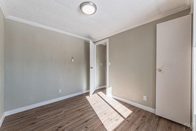 spare room featuring wood finished floors, baseboards, and ornamental molding