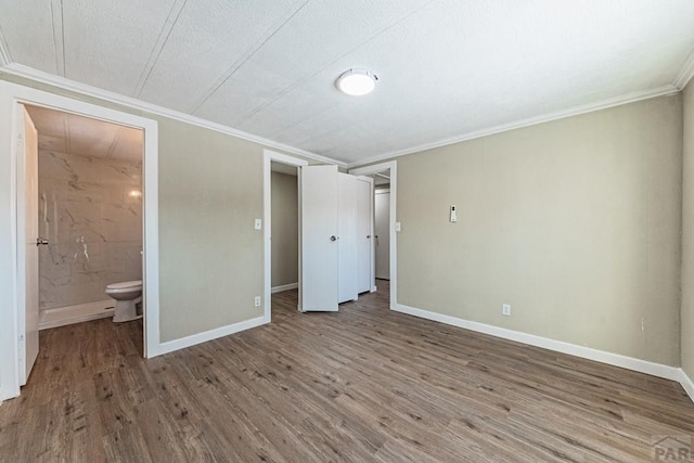 unfurnished bedroom featuring baseboards, wood finished floors, and crown molding