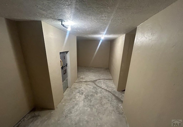 finished basement featuring a textured ceiling and a textured wall