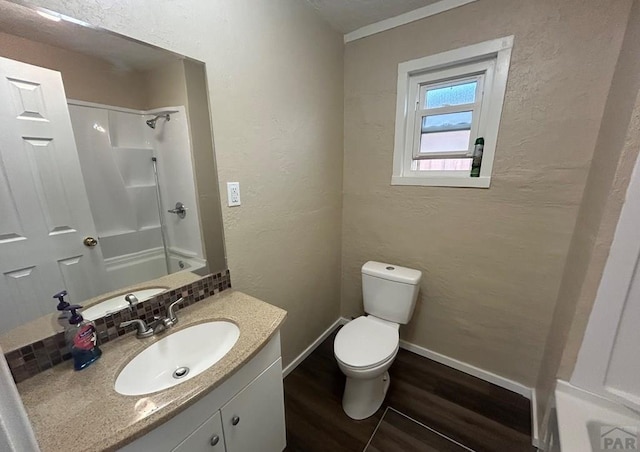 bathroom with wood finished floors, a shower, baseboards, vanity, and a textured wall