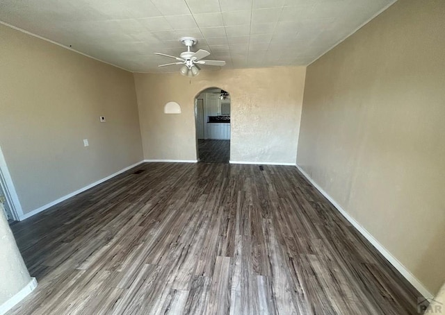 interior space with wood finished floors, a ceiling fan, arched walkways, and baseboards