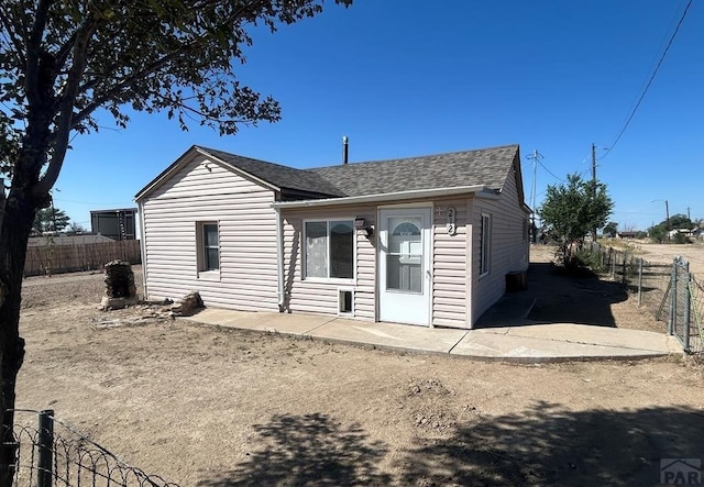 bungalow featuring roof with shingles and fence