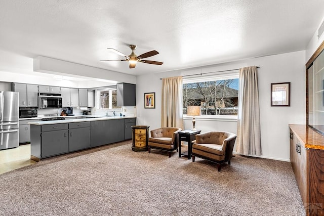 sitting room featuring ceiling fan, a textured ceiling, and light carpet