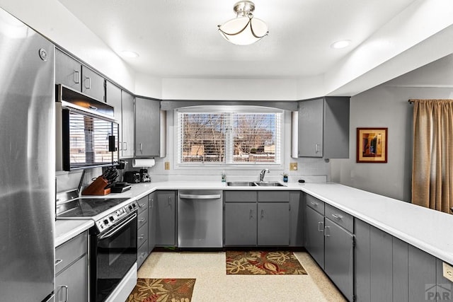 kitchen with gray cabinets, a sink, light countertops, appliances with stainless steel finishes, and backsplash