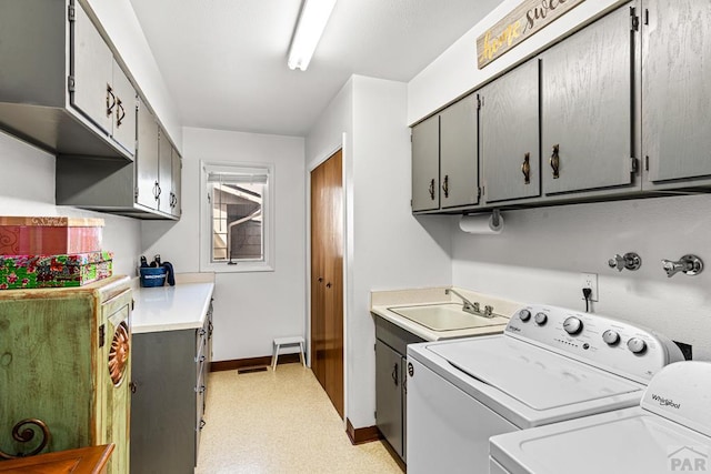 laundry room with washing machine and clothes dryer, cabinet space, baseboards, and a sink