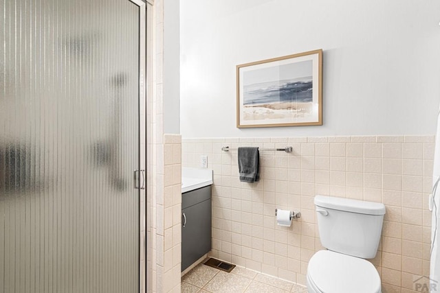 full bath featuring vanity, visible vents, a stall shower, tile patterned floors, and tile walls