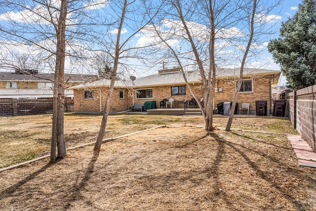 rear view of property featuring brick siding, a yard, and a fenced backyard