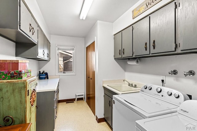 washroom with a sink, cabinet space, separate washer and dryer, baseboards, and light floors