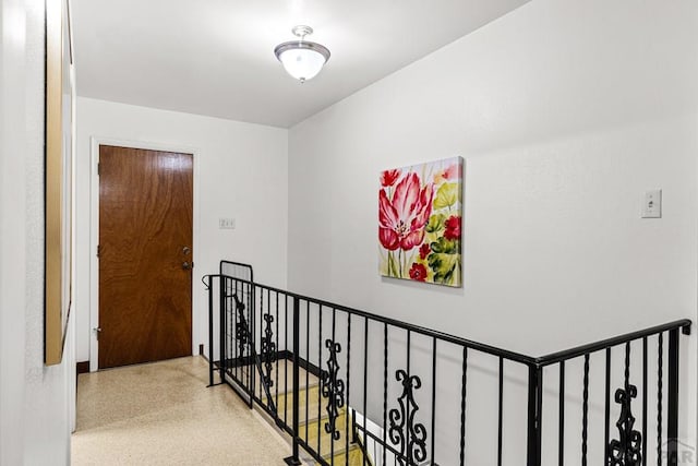 hallway featuring an upstairs landing and speckled floor