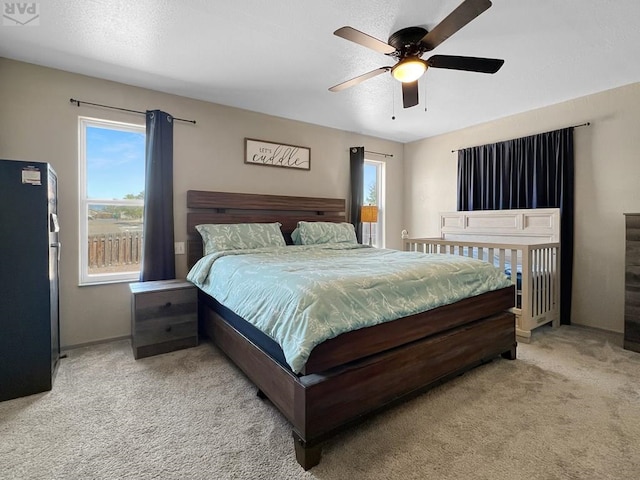 carpeted bedroom featuring ceiling fan, freestanding refrigerator, and baseboards