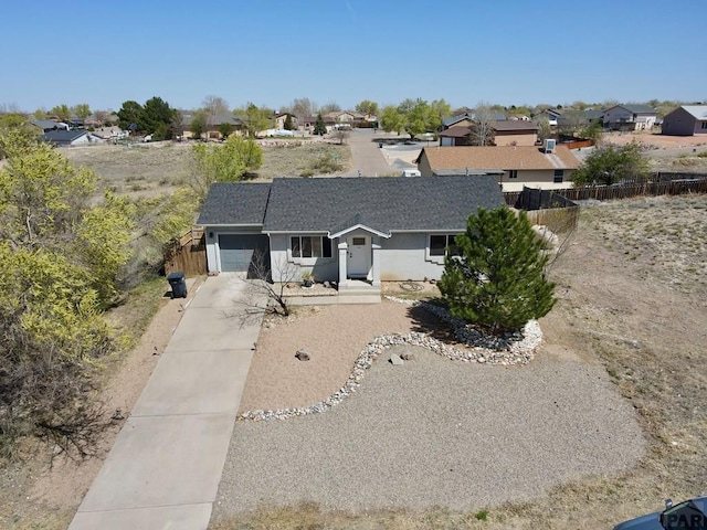 view of front of property featuring a garage, a residential view, fence, and concrete driveway
