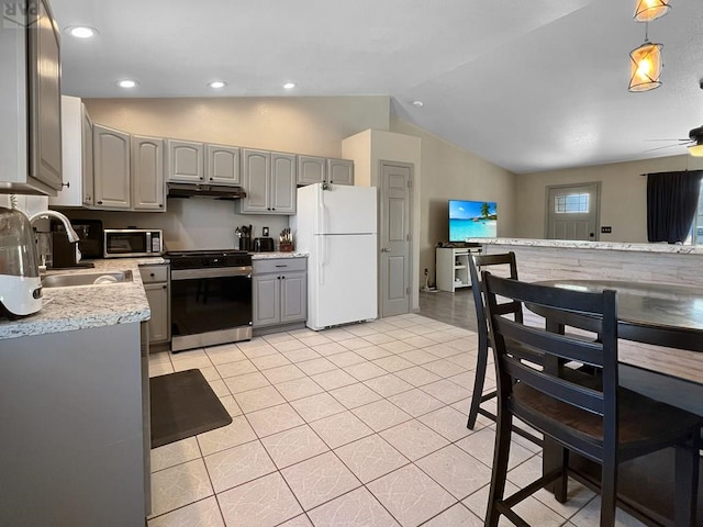 kitchen featuring freestanding refrigerator, gray cabinets, gas stove, stainless steel microwave, and lofted ceiling