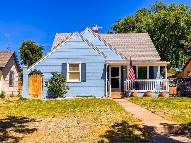 bungalow-style house featuring covered porch, a shingled roof, and a front lawn