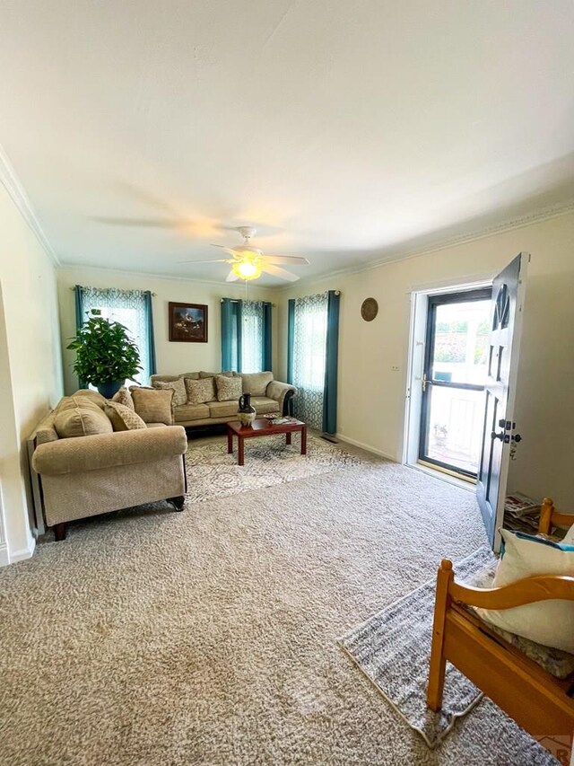 living room with ornamental molding, carpet flooring, baseboards, and a ceiling fan