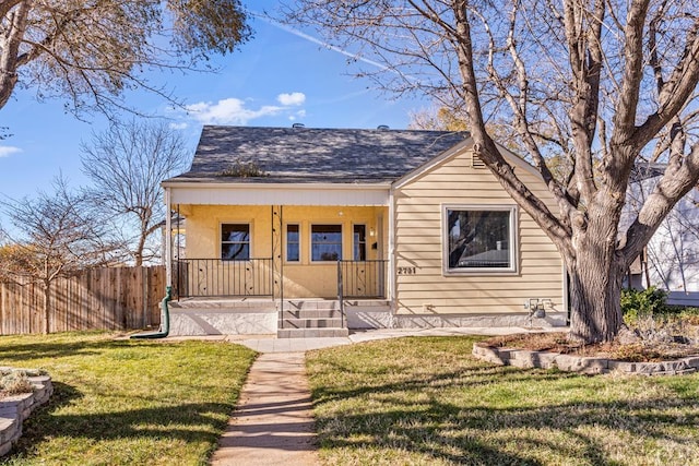 bungalow-style home featuring a porch, roof with shingles, a front yard, and fence