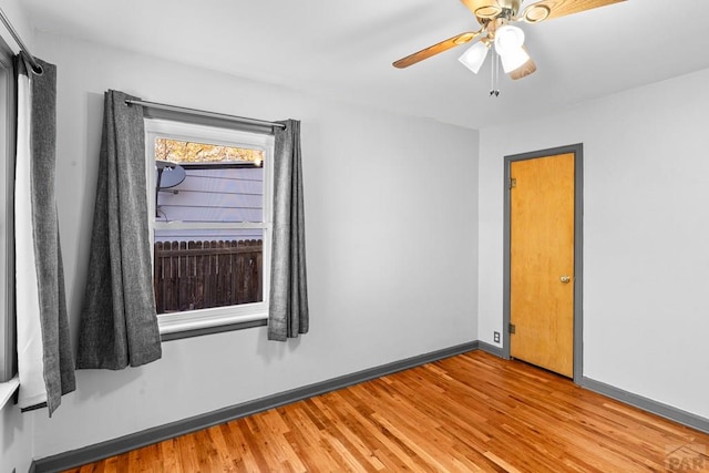 empty room featuring light wood finished floors, baseboards, and a ceiling fan