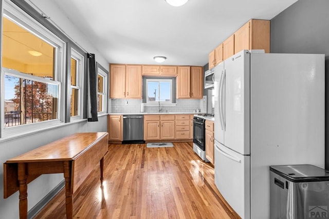 kitchen with light brown cabinets, stainless steel appliances, a sink, light countertops, and tasteful backsplash