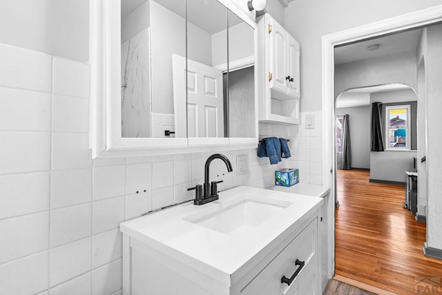 bathroom with wood finished floors, vanity, and tile walls