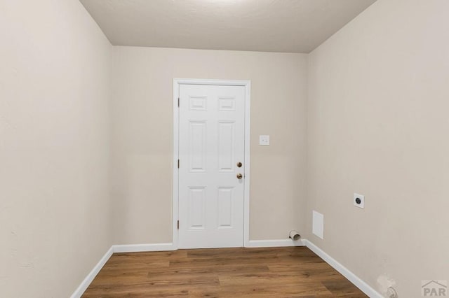 clothes washing area featuring laundry area, electric dryer hookup, baseboards, and wood finished floors