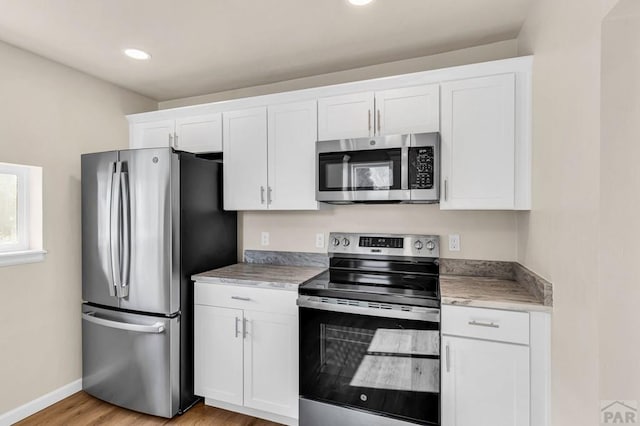 kitchen featuring light countertops, appliances with stainless steel finishes, white cabinetry, and baseboards