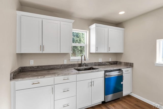 kitchen with stainless steel dishwasher, dark wood-style flooring, a sink, and white cabinets