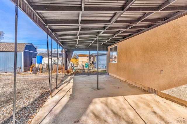 view of patio / terrace with a carport, a storage unit, an outdoor structure, and fence